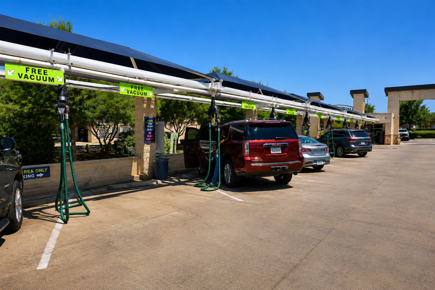 Free vacuum stations under long blue canopies with cars parked underneath